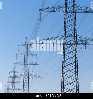 Power poles with high-voltage lines against a clear blue sky. Industrial landscape characterized by technology, Baden-Wuerttemberg, Germany Stock Photo