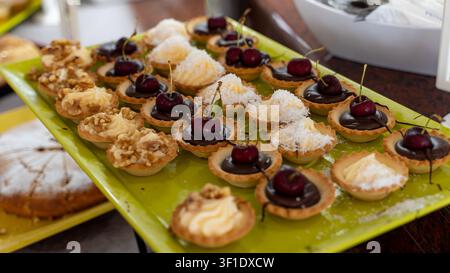 Assorted Mini Dessert Tartlets with Cherries on Buffet Table Stock Photo