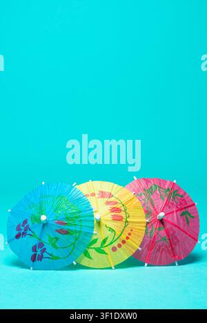 Colorful Paper Cocktail Umbrellas Arranged on Cyan Background Stock Photo