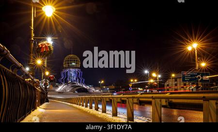Dominanta Tower on a winter night in Gorzow Wielkopolski, seen from the bridge with bright beams of lanterns and a road sign. Stock Photo