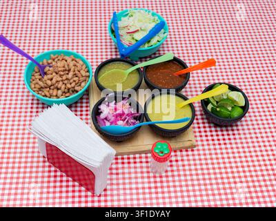 Authentic Mexican sauces and beans served in small bowls on a checkered tablecloth Stock Photo