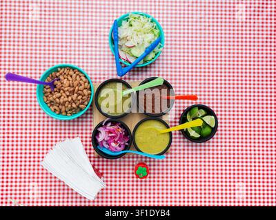 Authentic Mexican sauces and beans served in small bowls on a checkered tablecloth Stock Photo