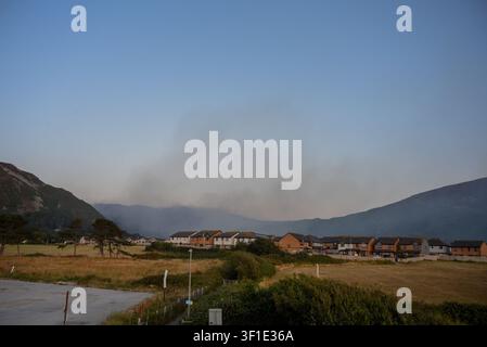 Dwygyfylchi, North Wales, UK. 12th July, 2026. Smoke continues to rise from Conwy Mountain behind homes in Dwygyfylchi, North Wales, UK, at sunset, hours after emergency services declared a major incident due to the ongoing wildfire near Sychnant Pass. Nearby residents had been evacuated and communities advised to keep windows and doors closed while firefighters worked to contain the blaze and protect surrounding communities, property and the environment. Credit: Geoff Wedge / Ģ����ý Live News Credit: Geoff Wedge/Ģ����ý Live News Stock Photo