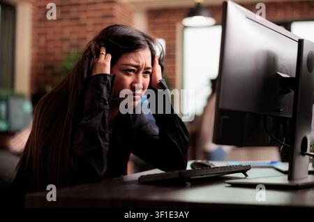 Exhausted engineer writes code after overtime while developing cloud computing data, HTML scripts and algorithms on a workplace computer inside an IT office. Stock Photo
