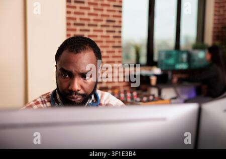 Software developer programs cloud computing data at a workplace computer while creating software, writing algorithms and supporting cloud computing development in an IT office. Stock Photo