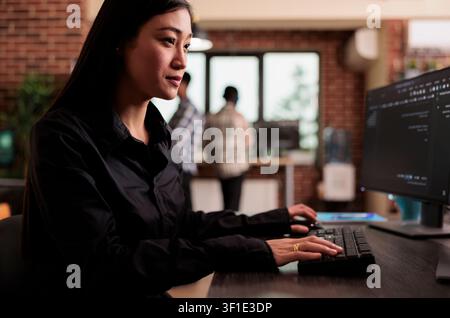 Software developer writing javascript code on terminal window, working with computer displaying coding algorithm, asian tech engineer programming big data in company office. Stock Photo