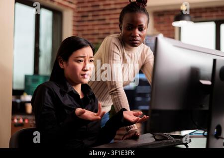 Programmers brainstorm software security ideas while developing cloud computing data, HTML scripts and algorithms on a workplace computer inside an IT office. Stock Photo