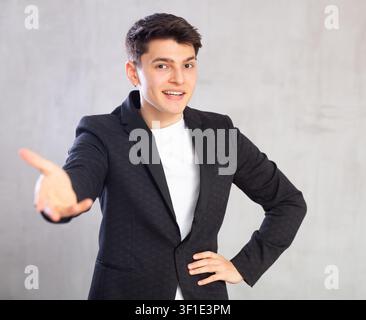 Smiling surprised young male student in suit jacket pointing at you.Portrait of guy pointing finger Stock Photo