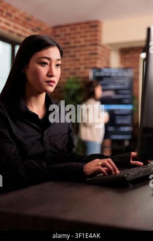 Asian developer checking HTML script on computer terminal while developers work with code, terminal windows and digital systems in an IT office focused on software production. Stock Photo