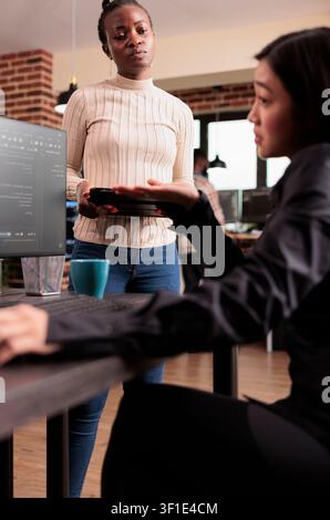 Software development team reviewing HTML code together in a programming workspace, connecting source code, database logic and collaborative development for a technology project. Stock Photo