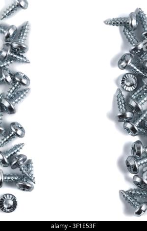 Metal screws scattered on a clean white surface. Sharp edges and shiny heads catch the light. Perfect for construction, DIY, or industrial design proj Stock Photo