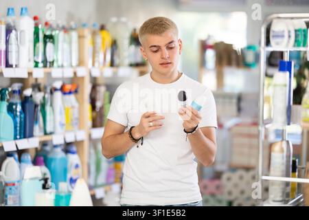 Nice young man customer buying deodorant and choosing between two bottle in store Stock Photo