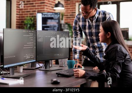 Diverse team of system engineers developing html code and cloud computing in it development agency, Asian software developer typing on keyboard to create artificial intelligence script. Stock Photo