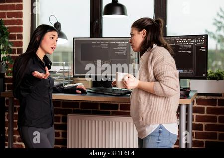 Diverse engineers developing software algorithm in server room while working with code, screens and digital infrastructure for software development. Stock Photo