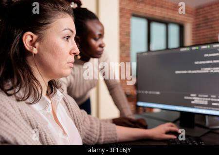 Engineers writing server code at workstation in server room while working with code, screens and digital infrastructure for software development. Stock Photo