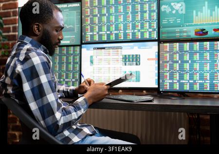 Stock manager writes progress updates on a clipboard for a hedge fund, connecting risk analysis and stock trading work in an office. Stock Photo