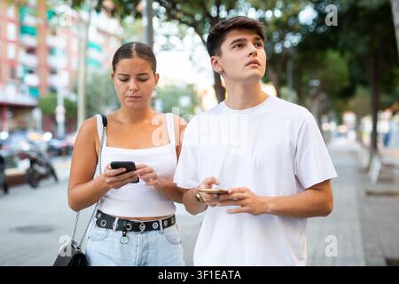 Young couple using smartphones while walking Stock Photo