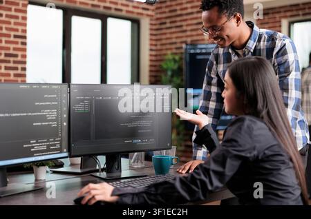 Programmers review security data and trace a cyber attack source, working together on system protection, firewall coverage and threat response as part of a natural cybersecurity workspace moment. Stock Photo