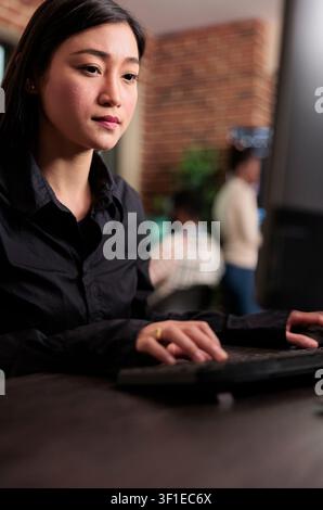 Asian system administrator updates firewall security and cloud storage encryption, maintaining stable infrastructure in a programming room, connecting security and technology within a clear. Stock Photo