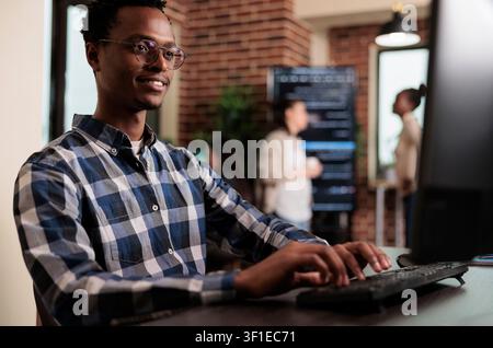 Smiling African American software engineer develops a machine learning algorithm for system security, network stability and binary encryption work. Stock Photo