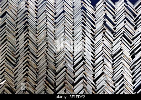 A close-up, full-frame shot of a weathered metal plate featuring a repeating herringbone pattern. The surface displays a striking contrast of dark bla Stock Photo