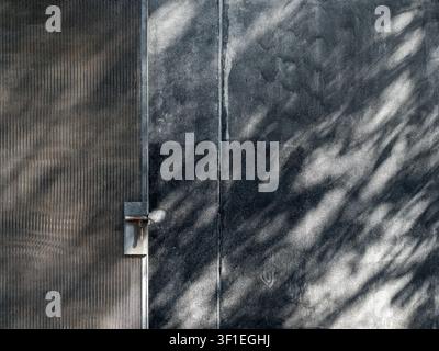 Industrial metal mesh gate and dark concrete wall with natural shadow, abstract texture background. Architecture, construction, industrial design, mod Stock Photo