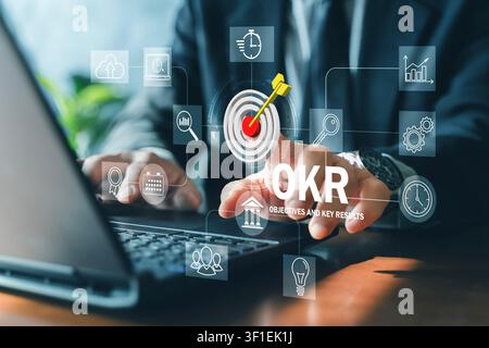 Business professional uses a digital OKR interface with target and analytics icons, representing objectives, key results, performance tracking, strate Stock Photo