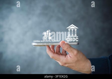 Hand holding a smartphone with CBDC and central bank digital currency icons, representing digital payments, fintech innovation, monetary systems, and Stock Photo