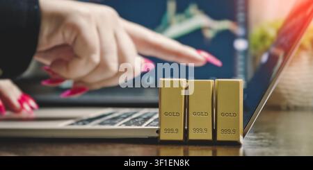 Online wealth management and gold trading concept. Businesswoman pointing at financial data on a computer screen. Stock Photo