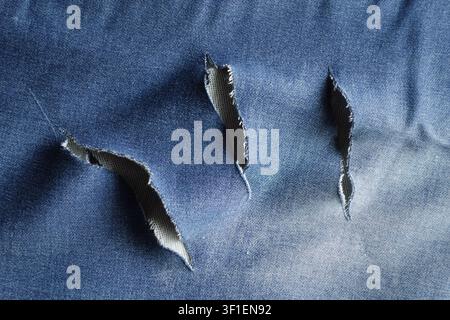 Torn fabric showing damage in blue denim material Stock Photo