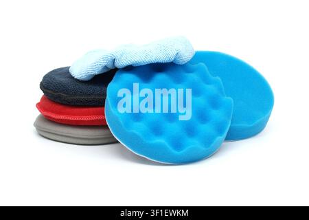 A set of colorful foam applicator pads and a blue microfiber towel arranged on a white background for automotive detailing tasks Stock Photo