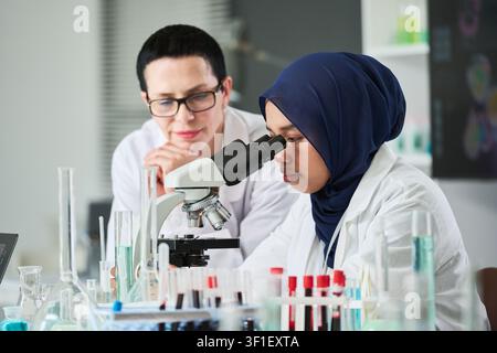 Muslim Female Researcher Using Microscope in Medical Lab Stock Photo