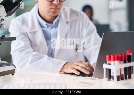 Midsection of Male Researcher Analyzing Lab Data on Laptop in Laboratory Stock Photo