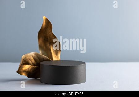 Elegant Minimalist Display with Black Pedestal and Gold Leaves for Luxurious Product Presentation Stock Photo