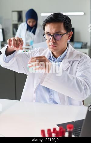Asian Male Scientist Analyzing Liquid Sample in Medical Laboratory Stock Photo