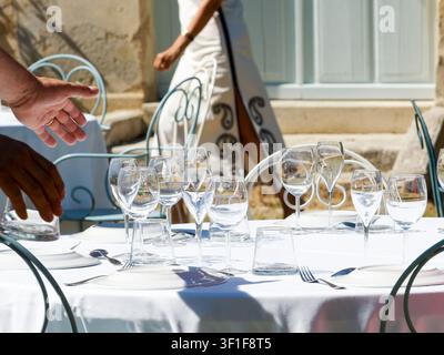 Outdoor reception table set with wine glasses, white table linen and metal chairs Stock Photo