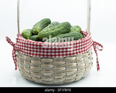 Fresh organic cucumbers in a wicker basket isolated on white. Homegrown vegetables from a summer garden harvest Stock Photo