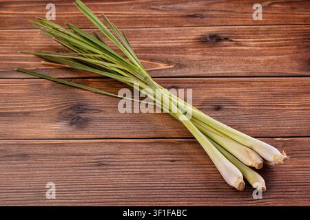 Fresh lemongrass stalks arranged diagonally on dark wood background. Natural lighting highlights green pale yellow tones. Rustic composition ideal for Stock Photo