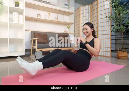 Asian woman doing core abdominal workout on mat at home for fitness Stock Photo
