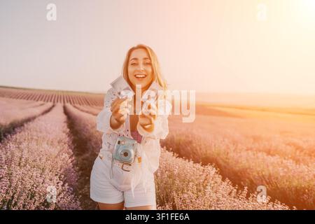 Lavender field woman holding instant photographs and an analog camera in the beautiful sunset light Stock Photo