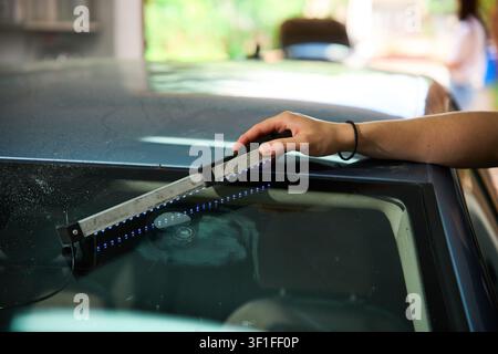 Windshield UV Resin Curing. Windshield repair. Automotive technician holds ultraviolet lamp over broken car glass. Mechanic cures resin inside windshi Stock Photo