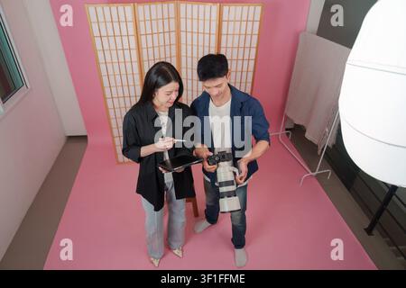 Asian creative team reviewing photos on camera in studio for behind the scenes workflow Stock Photo