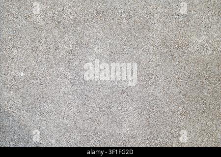 A detailed view of a surface covered in small, light grey stones and gravel, showcasing a rough, granular texture Stock Photo