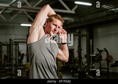 Athletic Man Stretching before Workout in Gym for Fitness Training Stock Photo