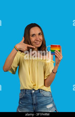 Woman smiling, highlighting a rainbow colored mug and wristband, expressing pride Stock Photo