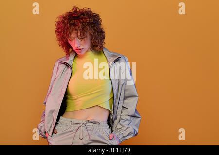 A stunning young woman with red curls displays her chic style in a vibrant setting. Stock Photo
