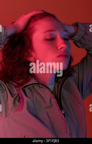 A young woman with stunning red curls poses elegantly, exuding confidence and style. Stock Photo