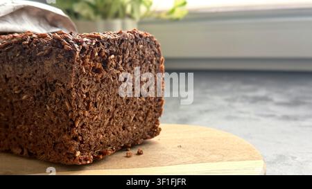 Freshly baked seed bread loaf on a wooden cutting board with a blurred background  Stock Photo