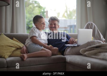 Happy father and son talking on the couch at home Stock Photo