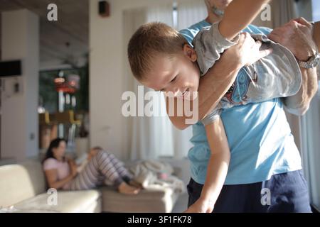 Playful father holding his laughing son at home Stock Photo